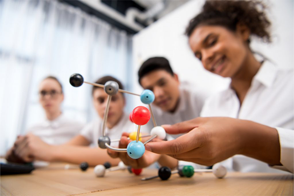 Students at a table working on a model of a molecule made from little balls and sticks.