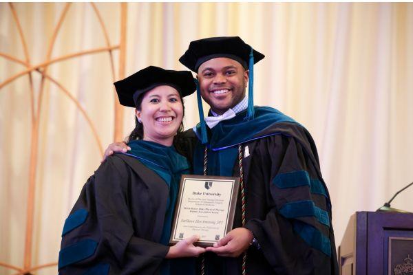 Faculty member in a grad robe, with a new graduate in a graduation robe