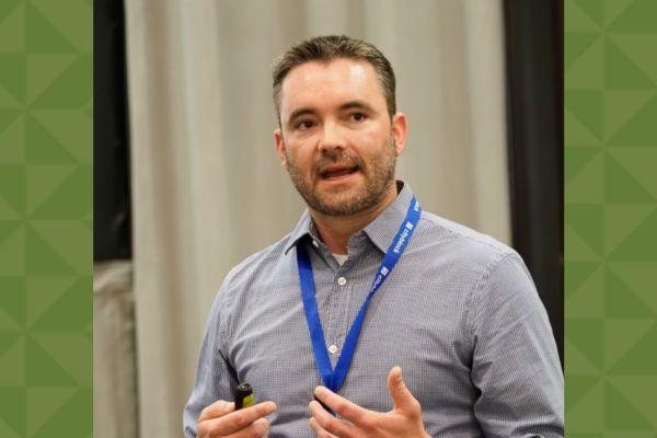 A man with a lanyard on and talking to a group