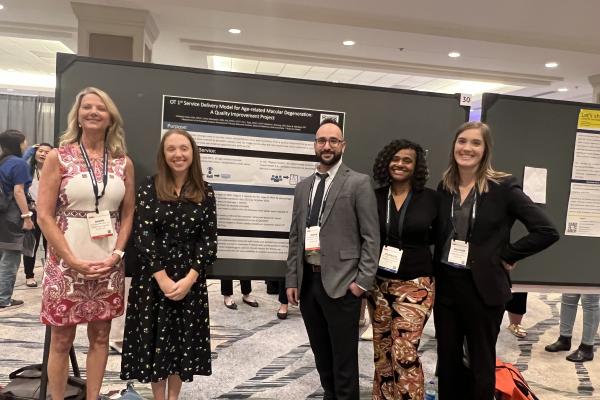 Five people in front of a conference poster