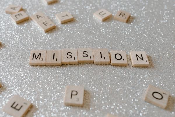 The word "mission" spelled out in Scrabble tiles on a sparkly background