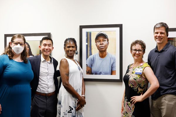Butterfly Miles, center, poses near her portrait with the team during the opening of the Untold Stories Exhibition at the Duke University Medical School Library in Durham, 