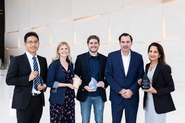 5 people standing and holding awards