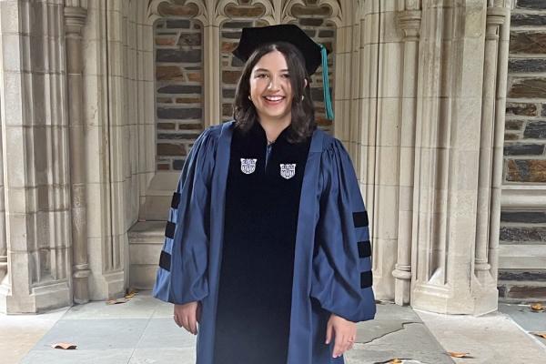 Caroline in her graduation cap and gown beside Duke Chapel