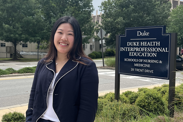 Phoebe standing next to the sign for Duke IPE building that houses the OTD program