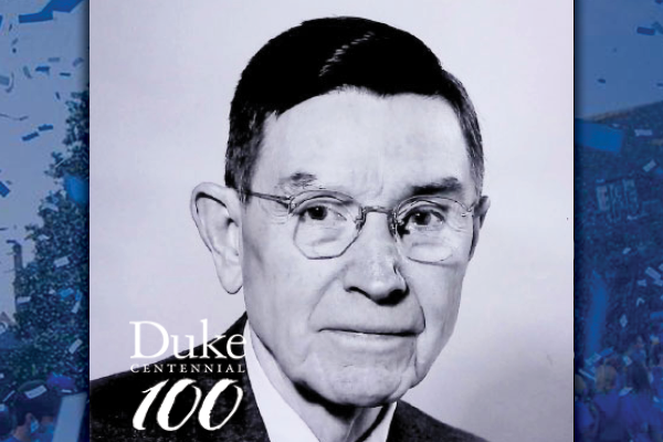 A black and white portrait of an older man with dark hair wearing glasses.