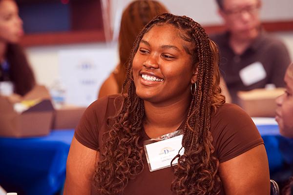 a woman with a name tag on smiling during a conversation while seated at a table