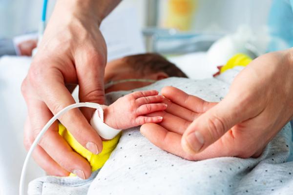 Closeup up adult's hands caring for an infant