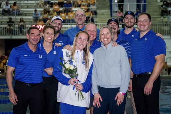 kyra posing with a group of people, holding a bouquet