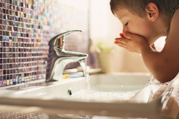 A child washing their face in running water