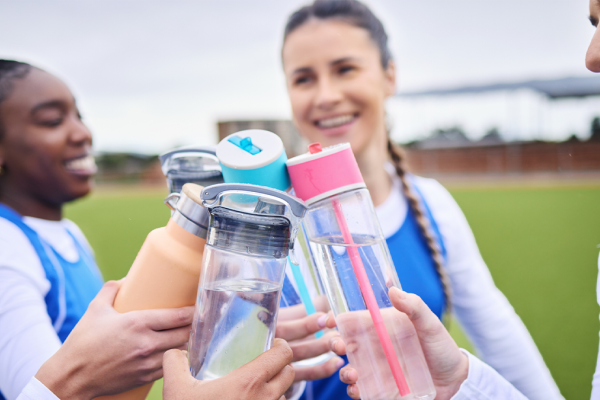 Three young teen girls toasting with their water bottles. 
