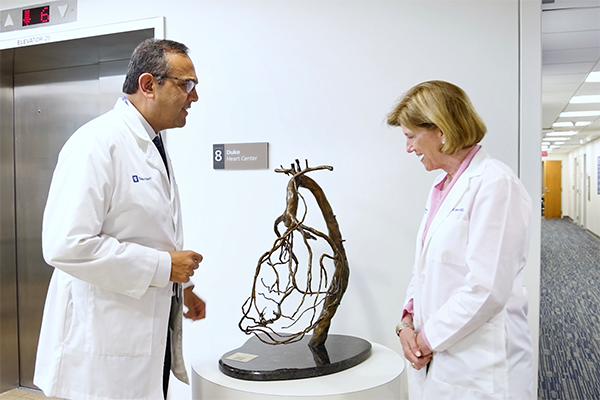 Manesh Patel, MD and Mary Klotman, MD looking at a small sculpture in a clinic hallway