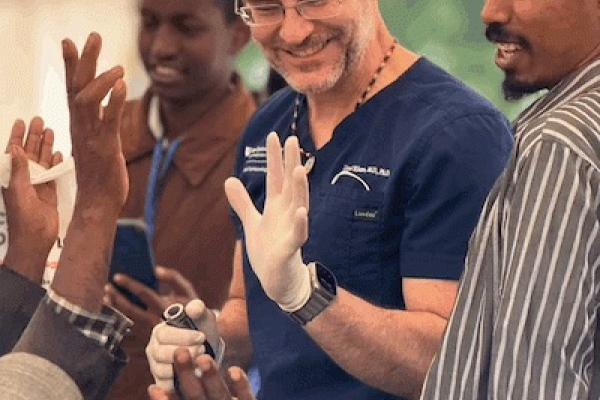 Dr. Lloyd Williams smiles and shares a high five in a crowd of people 
