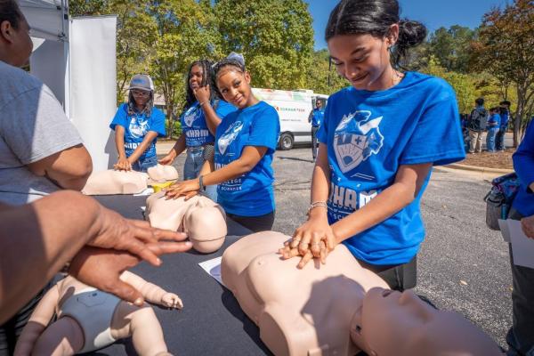 Students practice administering CPR with mannequins during the Early College for Health Sciences ribbon-cutting event