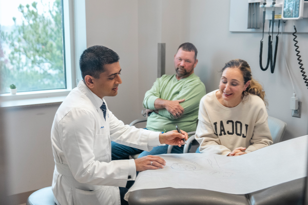 Physician consulting with patients in an exam room. 