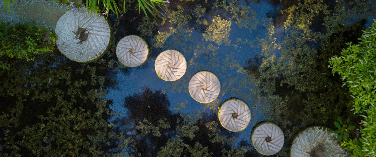 Millstones as stepping stones across a pond