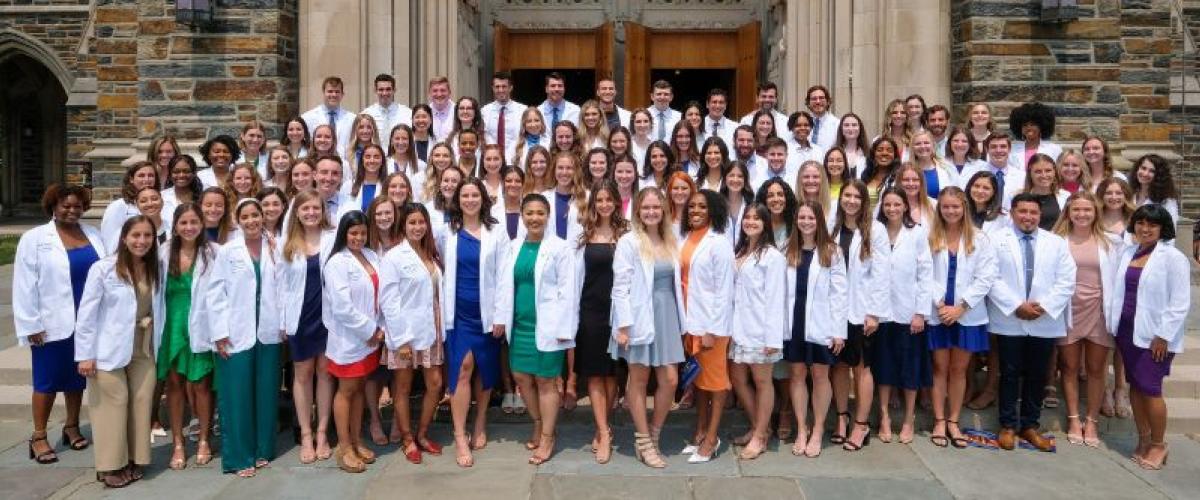 Large group with white coats in front of the Duke Chapel