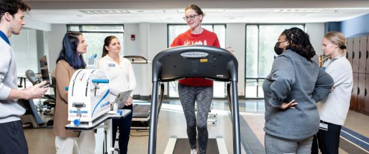 Five DPT students working with a community volunteer on a treadmill
