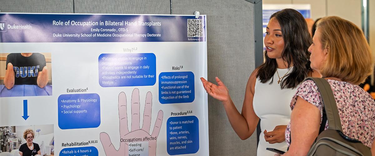 a student explaining her project poster to a woman