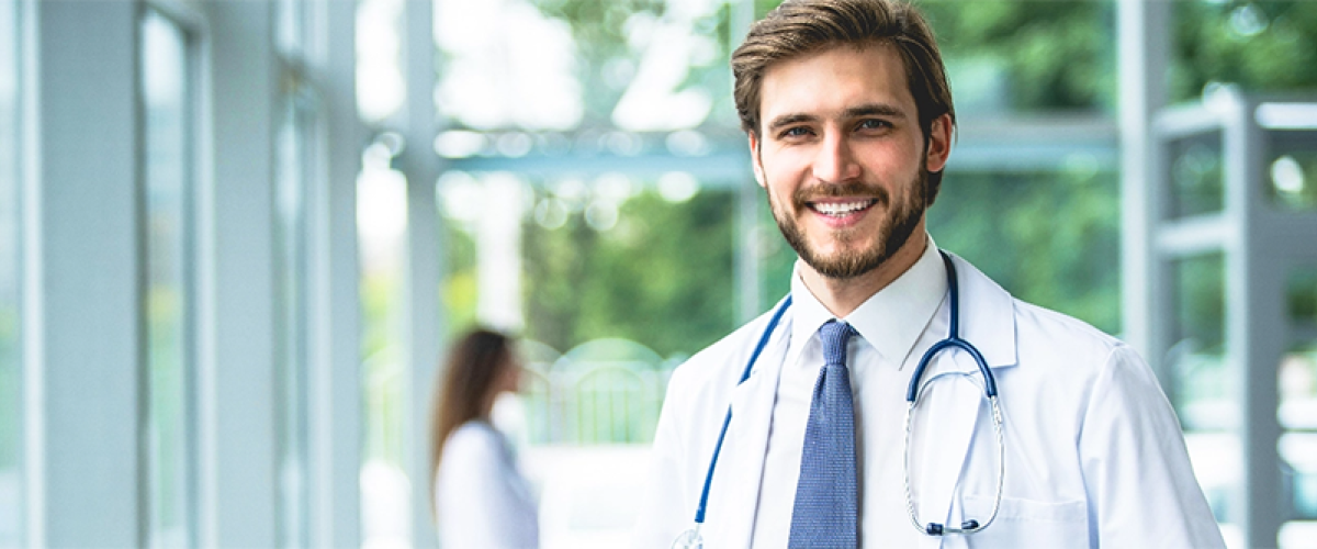 Young bearded physician standing in a brightly lit atrium