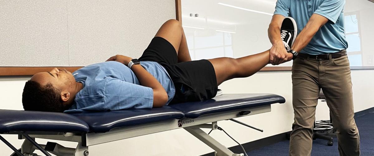 a man laying on a plinth table with a therapist holding his foot