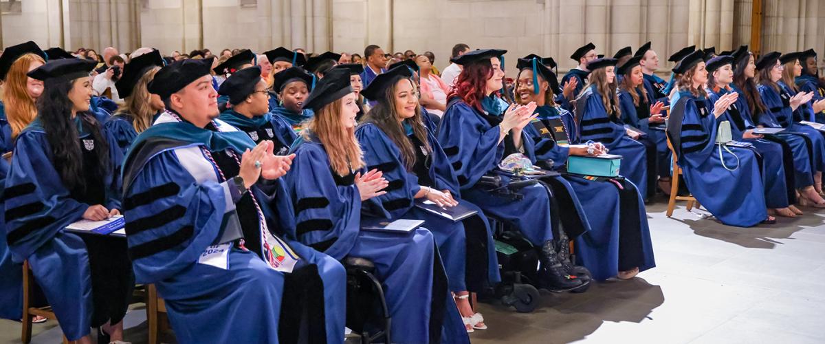 Duke OTD graduates in caps and gowns seated in Duke Chapel