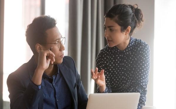 Man and woman talking to each other in front of computer