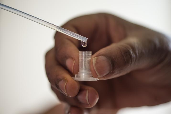 Hand of a Black person holding a small vial for lead testing 