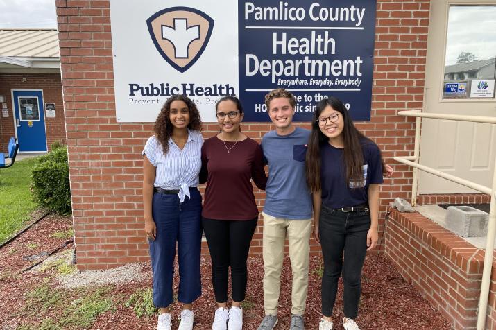 four students standing infront of sign