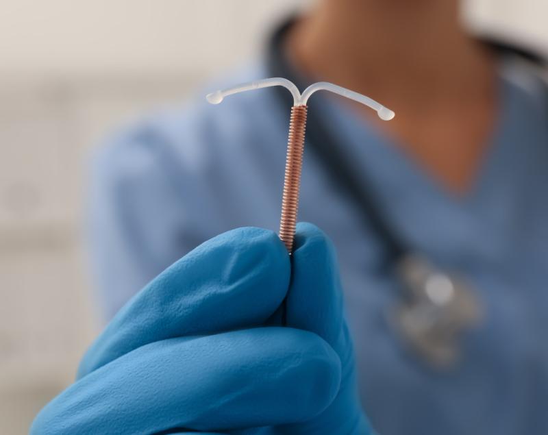 gloved hand holding up an IUD