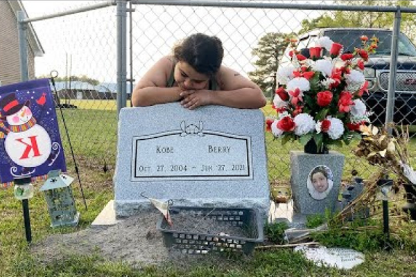 Young girl leaning on a gravestone mourning the deceased.