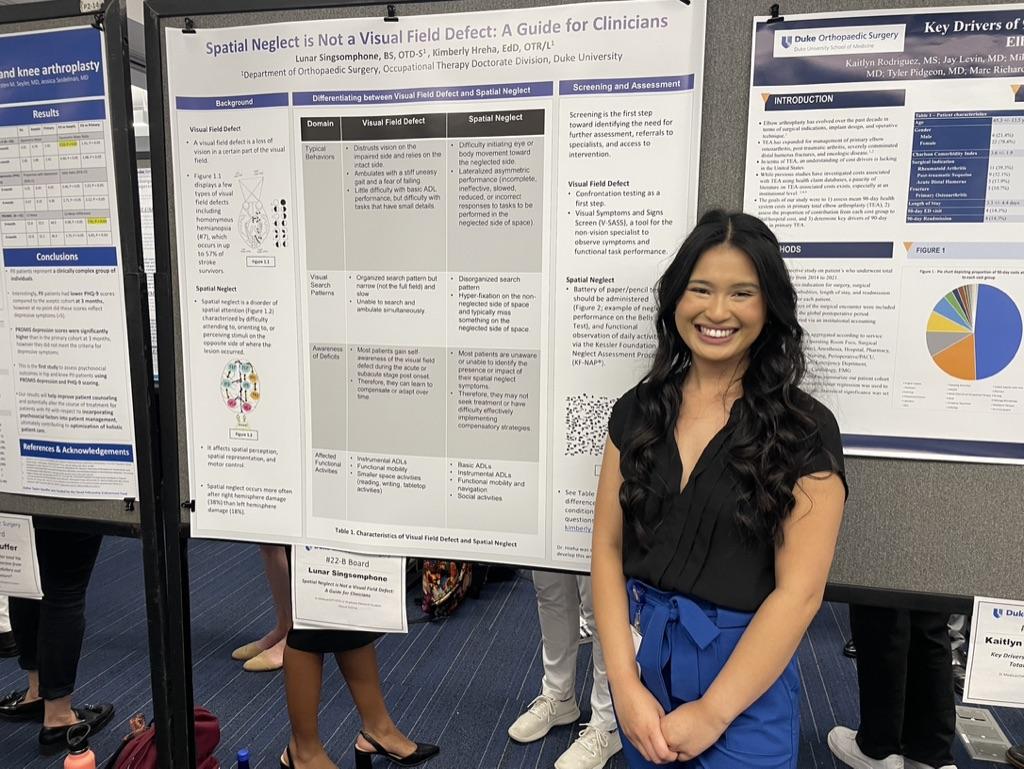 A student standing with her research poster