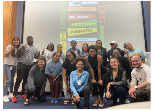 A group of students mostly kneeling in front of a screen 
