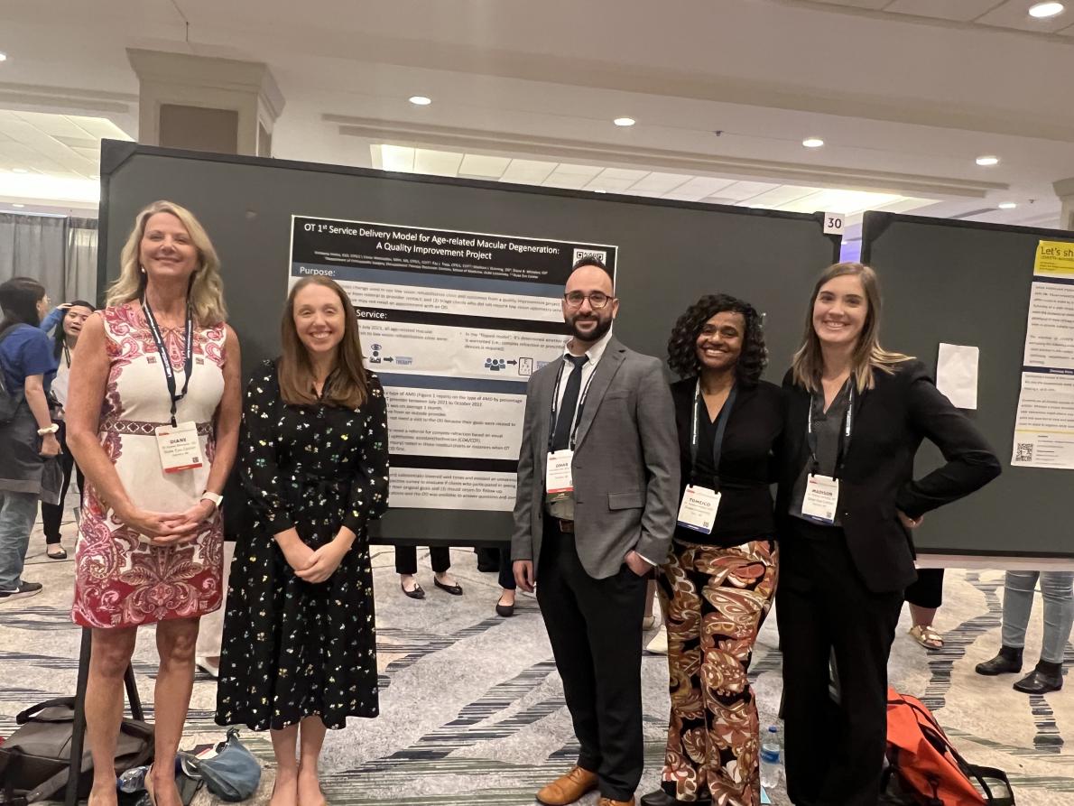 Five people in front of a conference poster