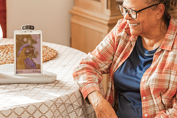 older woman at a table with a handheld standing on it. 
