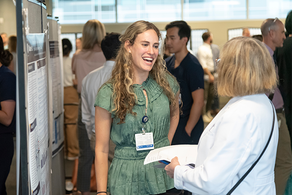 woman student speaking with a faculty member in front of her research poster