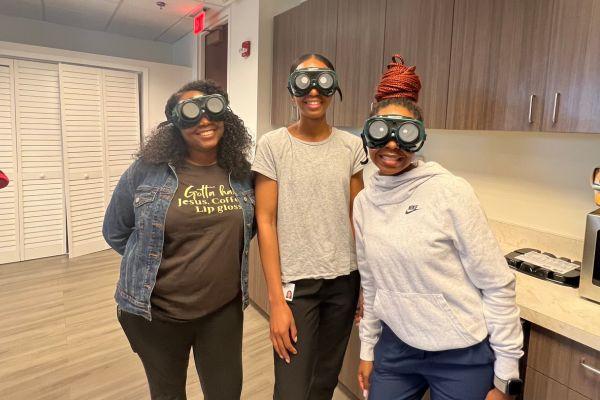Three students with low vision googles on in a lab setting 