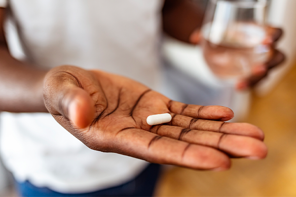 Brown person's palm holding a pill.