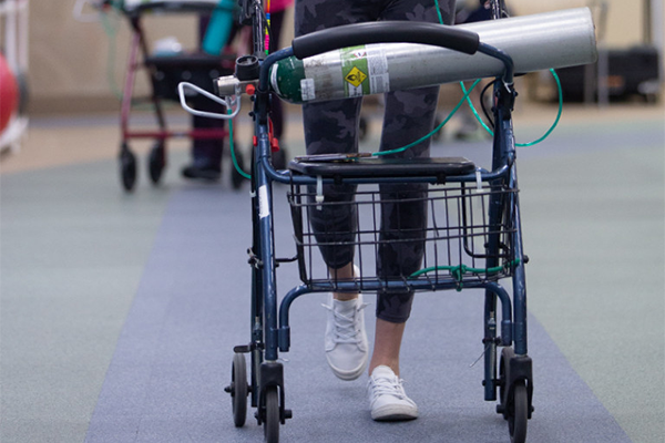 legs of a person using a walker with an oxygen tank in the basket