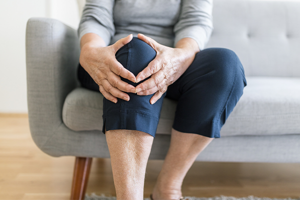 Elderly woman's hands resting over her bent knee