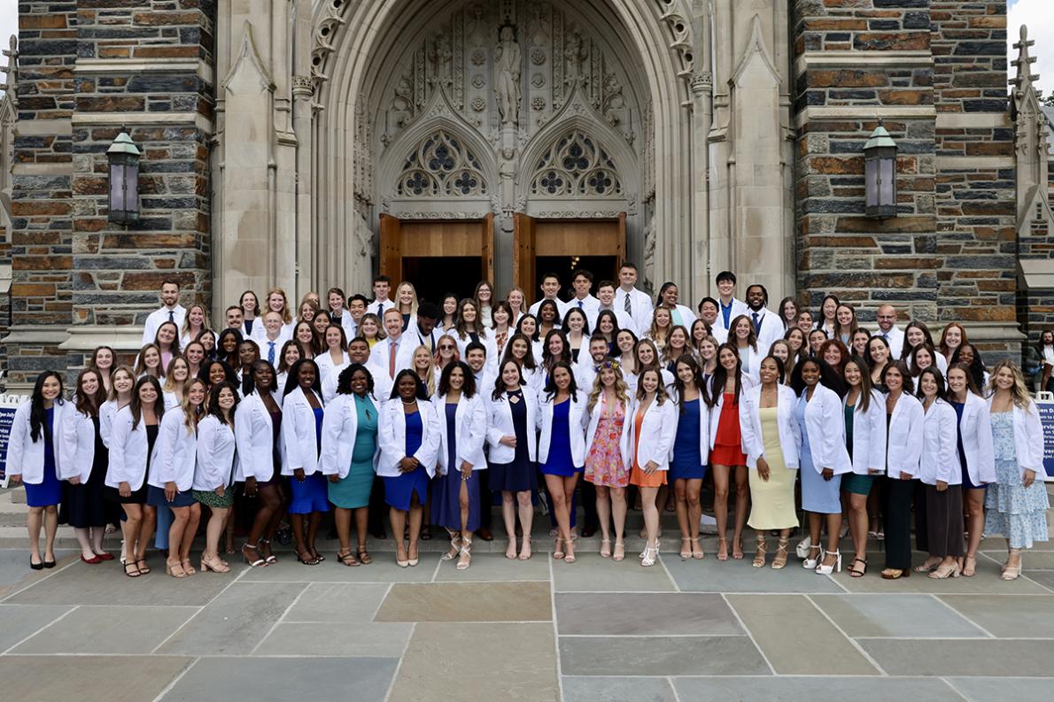 the Duke DPT class poses for a photo in front of Duke Chapel wearing their white coats