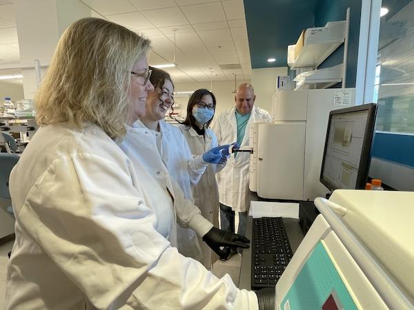 scientists in lab coats around a computer