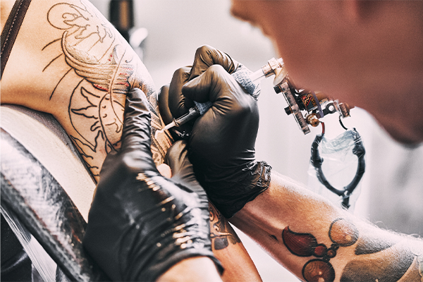 tattoo artist tattooing an arm. 