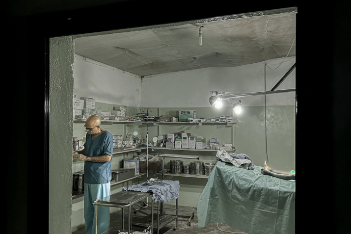 A man at preparing for work in a sparsely equipped operating room.