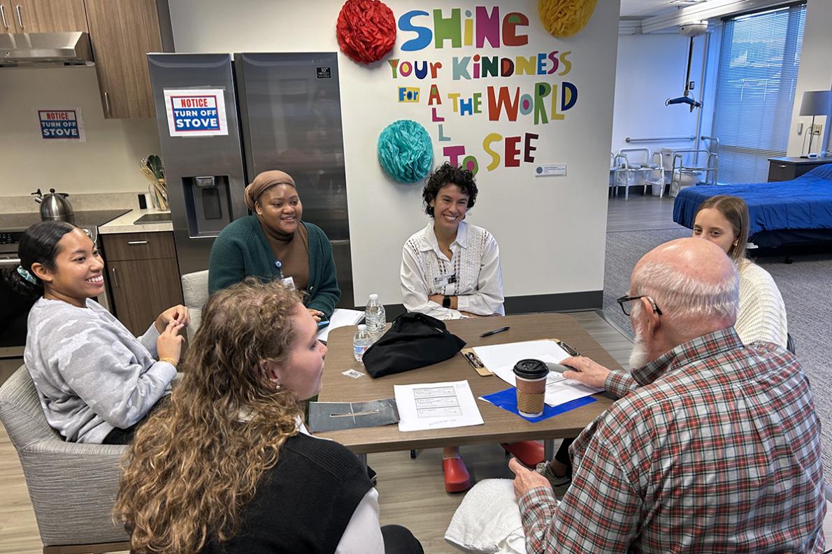 occupational therapy students and a client volunteer sitting at a table talking and smiling