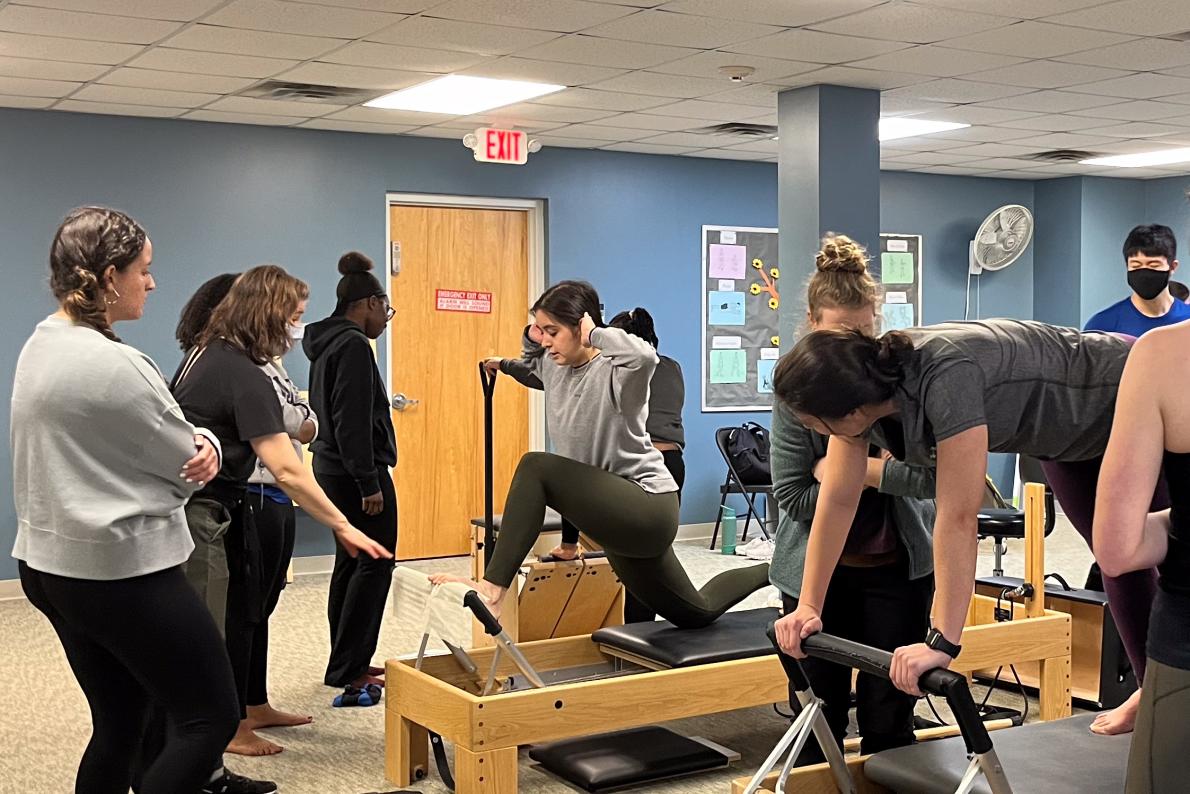 people using physical therapy equipment while students look on