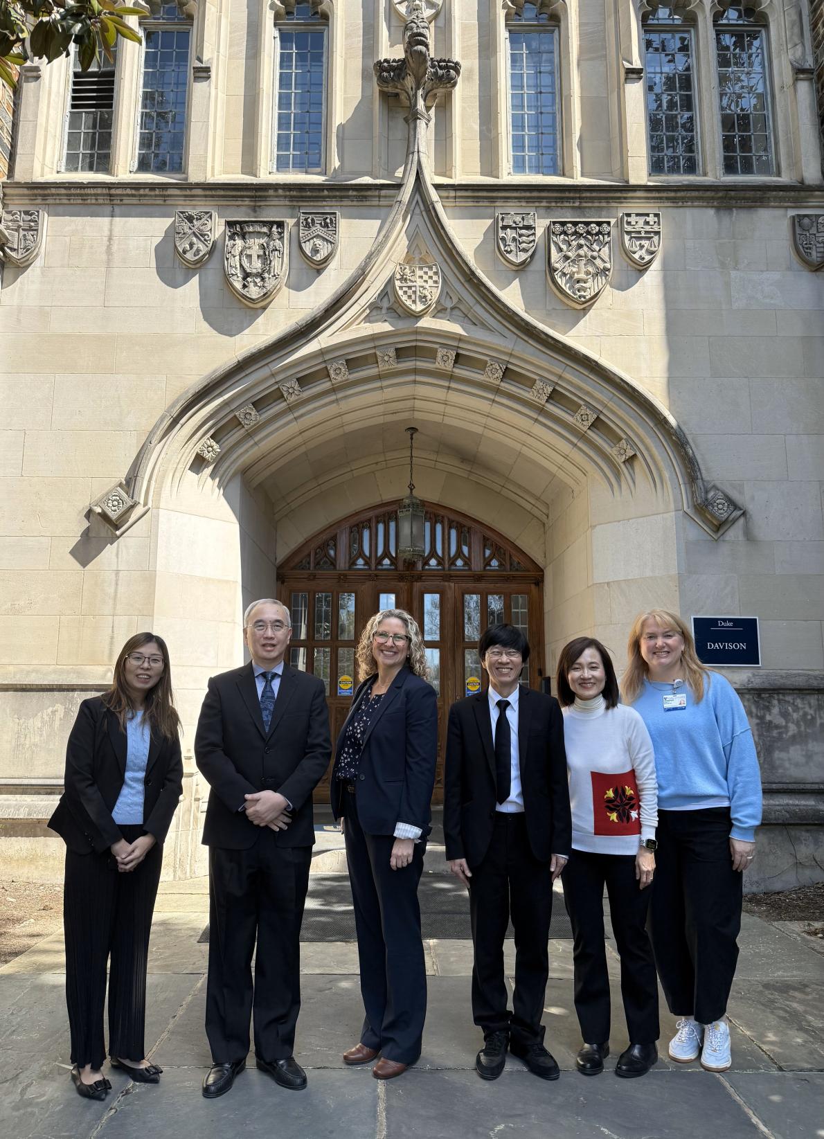 Group of six people standing in front of a building entrance