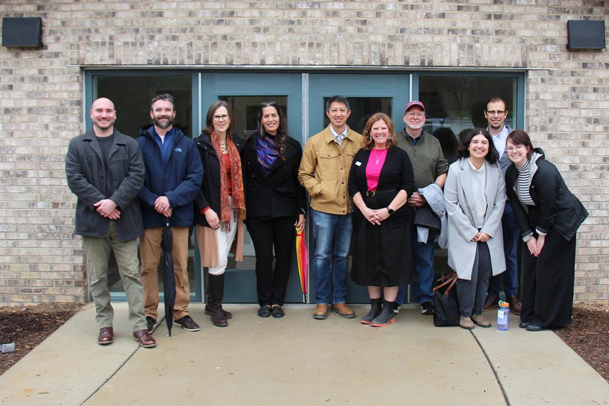 10 people standing in front of a building entrance posing for a photo