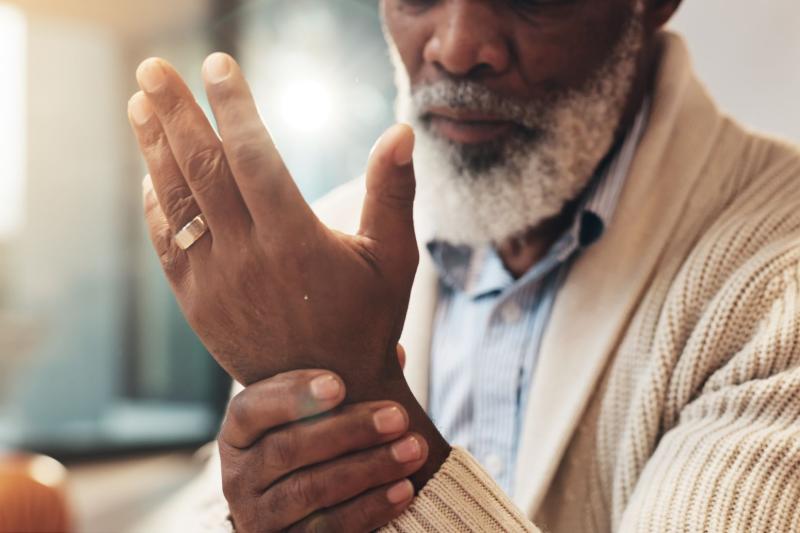 Graying bearded Black man feels his wrist as if it's tender