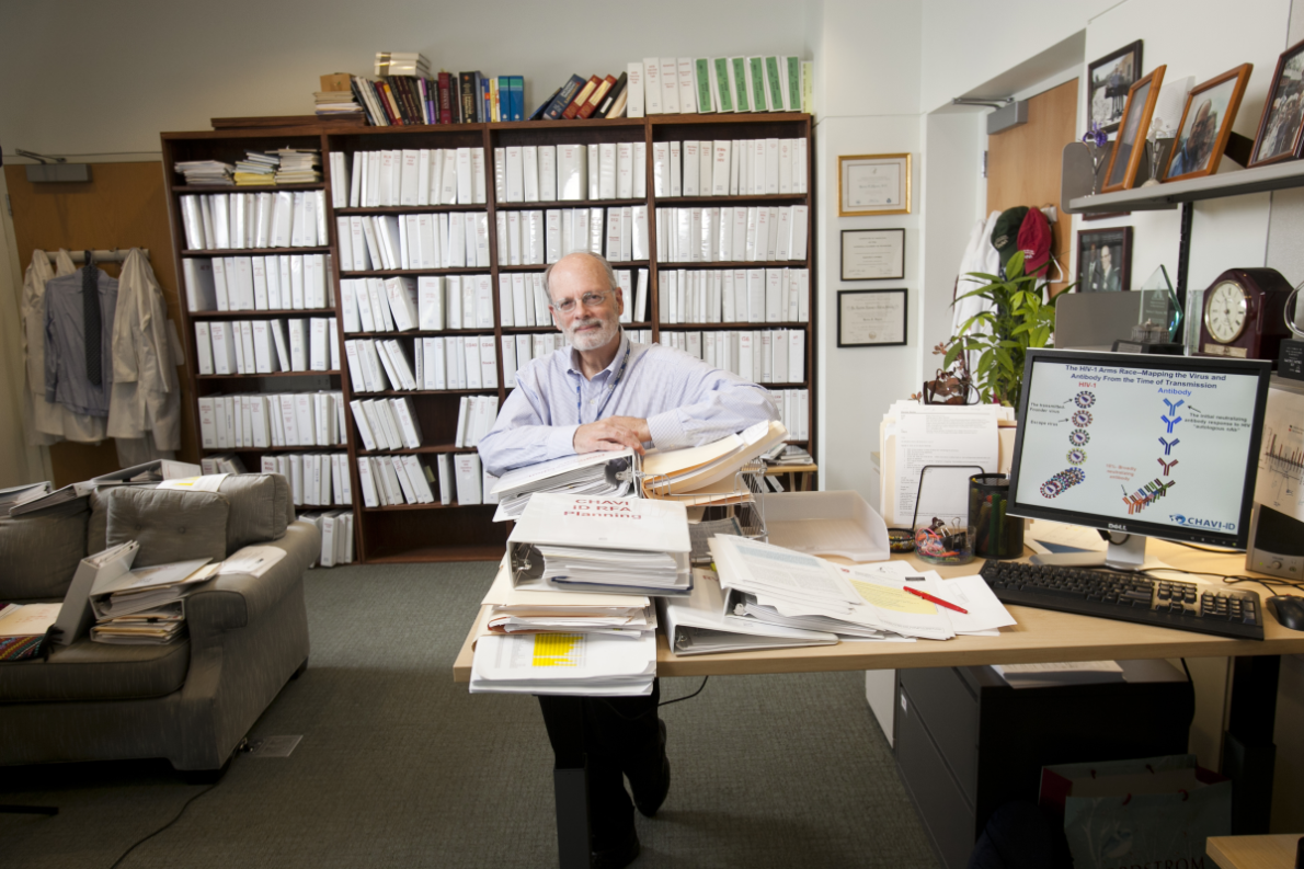 Barton Haynes in his office surrounded by bookcases and publications
